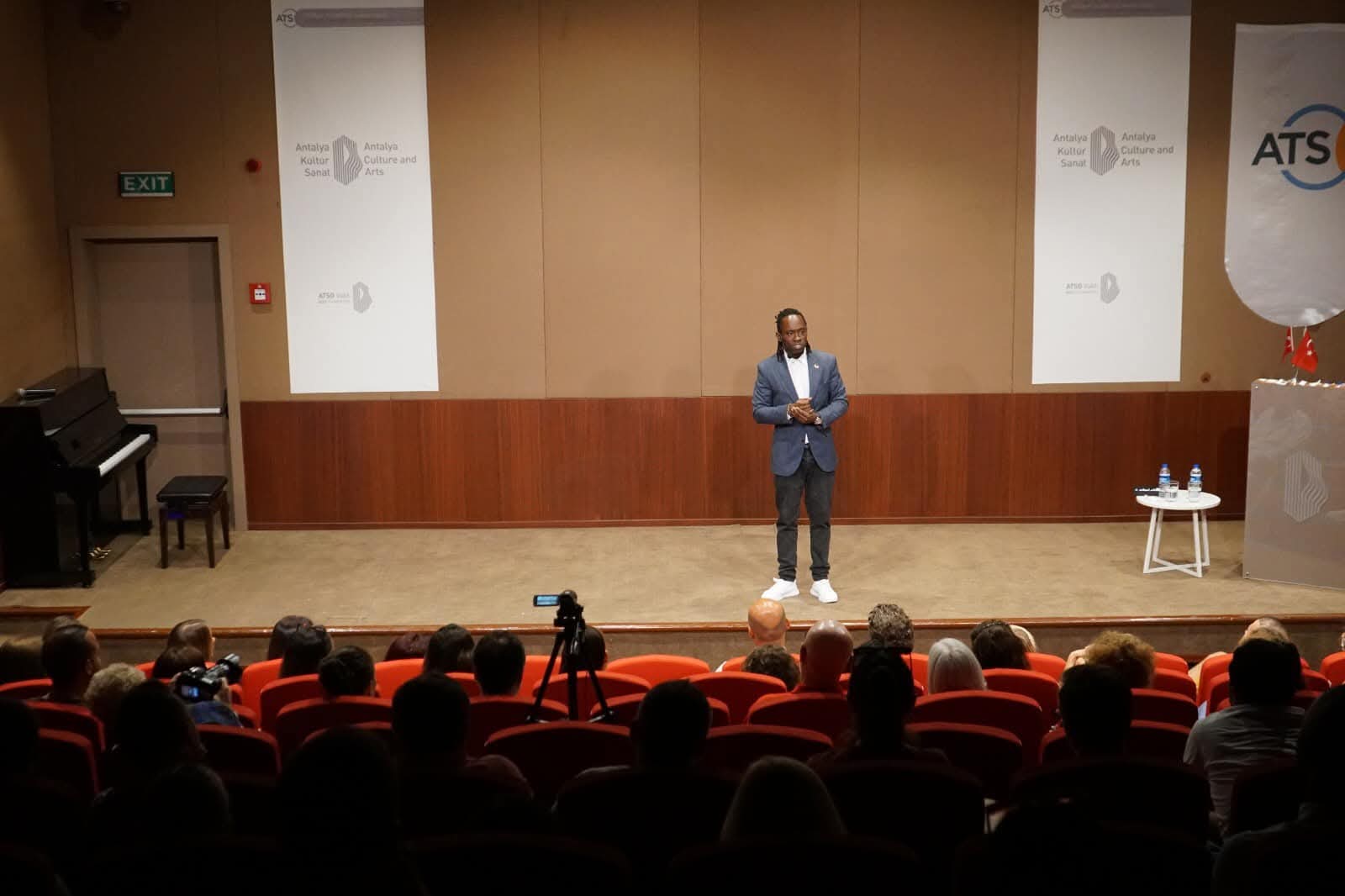 Steven Dossou on stage in front of a full auditorium in Antalya
