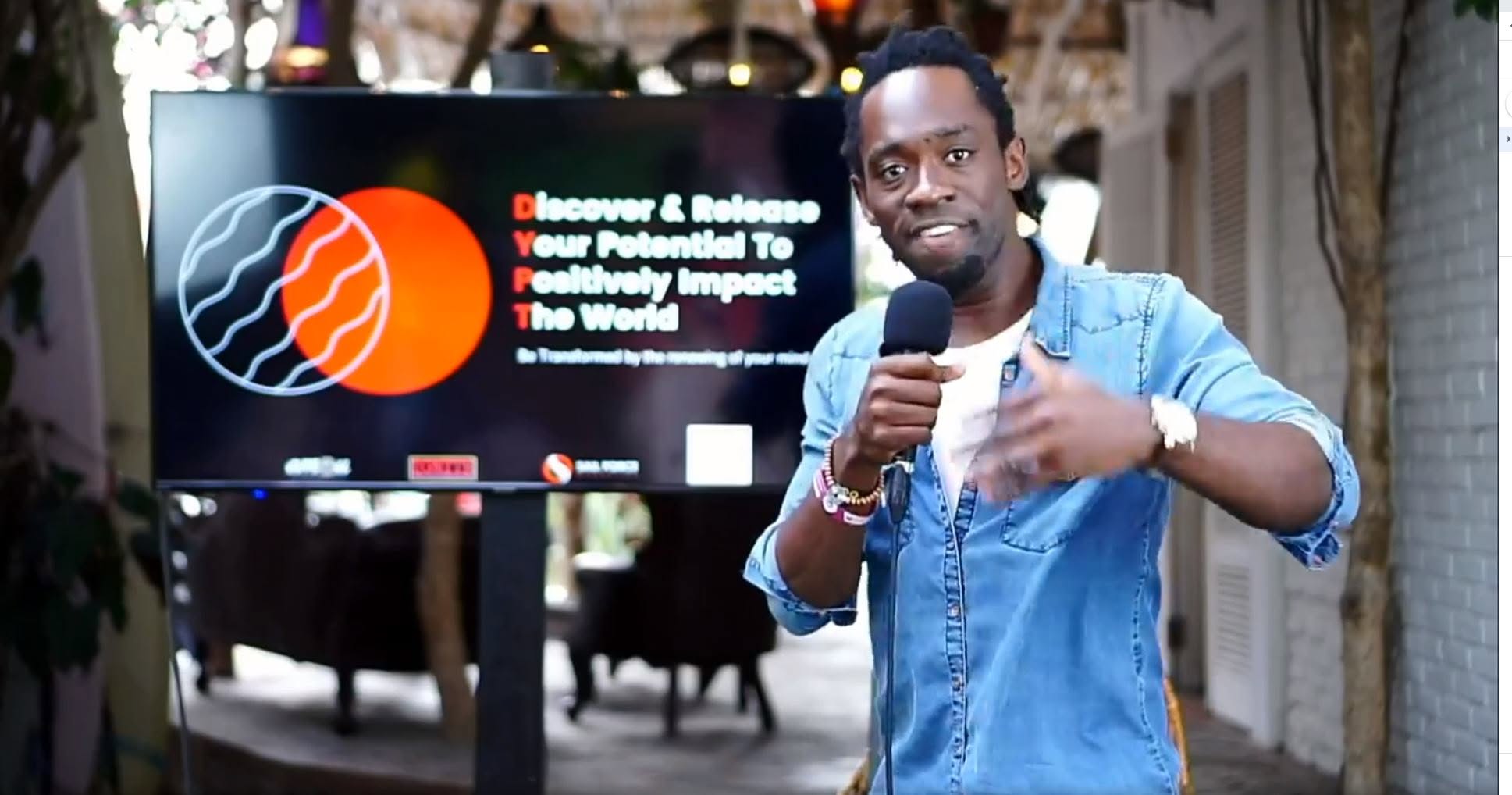 Steven Dossou speaking with a microphone beside a presentation screen