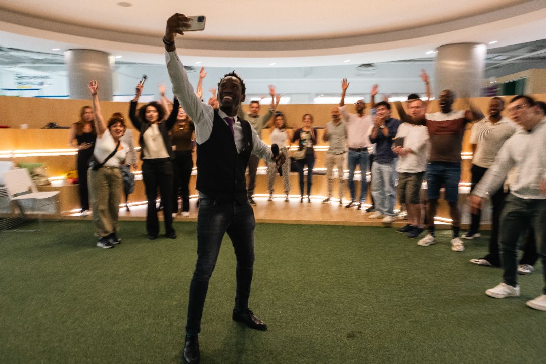 Steven Dossou taking a selfie with a cheering audience